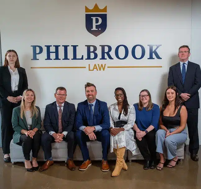eight philbrook law team members pose in business attire beneath the philbrook law logo